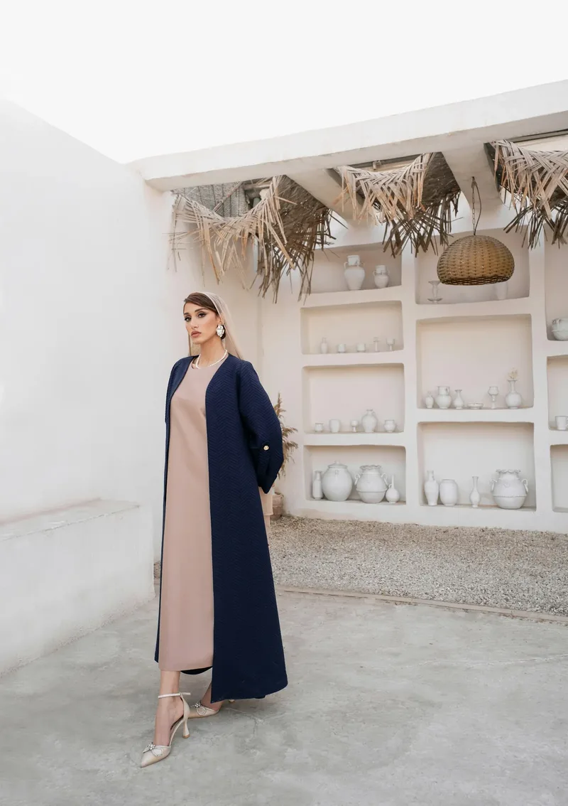 A beige dress under a navy abaya